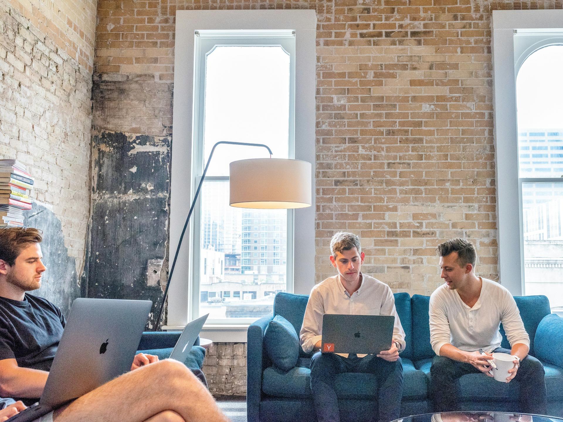 Several people seated together, intently looking at their laptops, sharing ideas and working on a project.